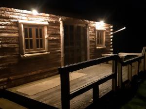 a wooden cabin with a porch at night at The Sunset Cabin in Beccles +5 photos