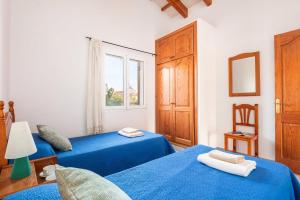 a bedroom with two blue beds and a window at Villa Maru II by Villa Plus in Cala en Porter +18 photos