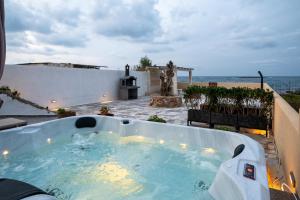 a hot tub on a patio with the ocean in the background at Sandy Steps Beachfront Apartments in Malia