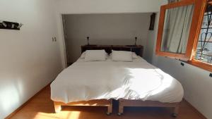 a bedroom with a large bed with white sheets and a window at Popo Country House in Atlautla
