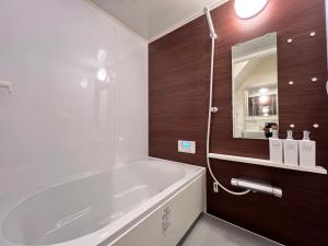 a bathroom with a white tub and a mirror at 内町3階 高松中心地 広いメゾネット貸切 2ベッドルーム 最大4名 in Takamatsu