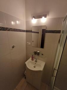 a white bathroom with a sink and a mirror at Apartmány ARIES in Nitra