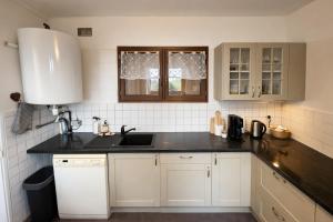 a kitchen with white cabinets and a black counter top at Maison paisible à Senlis in Senlis