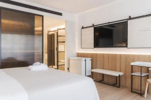 ein Schlafzimmer mit einem weißen Bett und einem Flachbildfernseher in der Unterkunft Olivia Lisboa Hotel in Lissabon