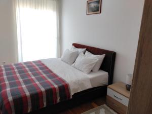 a bedroom with a bed with a plaid blanket and a window at AGA Apartman Podgorica in Podgorica