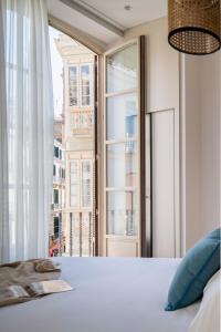 a bedroom with a bed and a large window at Líbere Málaga Plaza del Siglo in Málaga