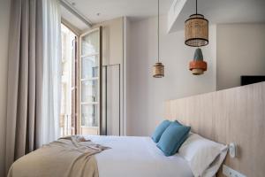 a bedroom with a bed with blue pillows and a window at Líbere Málaga Plaza del Siglo in Málaga