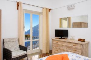 a bedroom with a bed and a television and a window at A la casa del cavaliere in Positano