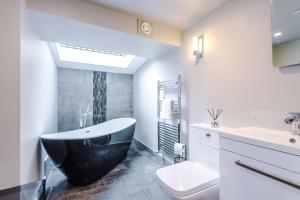 a bathroom with a black and white tub and a sink at Cosy Lake District Cottage - Walk to Windermere - Sleeps 6 in Windermere