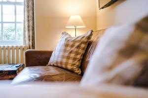 a couch with a pillow and a lamp in a room at Cosy Lake District Cottage - Walk to Windermere - Sleeps 6 in Windermere
