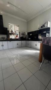 a large kitchen with white tile floors and a window at LOT 1423 Homestay Lonek-Batu Kikir in Bahau