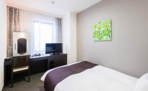 a bedroom with a bed and a desk with a television at Osaka Airterminal Hotel in Toyonaka +6 photos