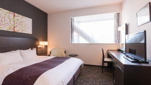 a hotel room with a bed and a desk with a television at Osaka Airterminal Hotel in Toyonaka