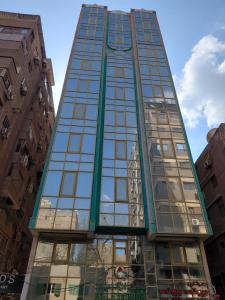 a tall glass building with a clock tower at Gulf Suites Cairo in Cairo