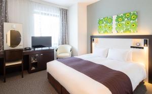 a hotel room with a bed and a television at Osaka Airterminal Hotel in Toyonaka