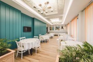 a dining room with white tables and chairs and a green wall at Crowne Plaza Budva by IHG in Budva