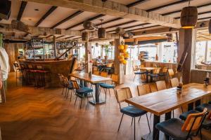 a restaurant with wooden tables and chairs and a bar at Veluwemeer Retreat in Hulshorst
