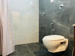 a bathroom with a white toilet and a shower at Bison Trails Valley View Kothagiri Ooty Tamilnadu in Kotagiri