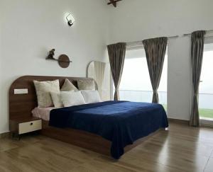 a bedroom with a bed with a blue blanket and a window at Bison Trails Valley View Kothagiri Ooty Tamilnadu in Kotagiri