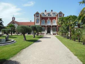 a large house with palm trees in front of it at La Maison Coloniale - 15 Personnes - Piscine in Artagnan