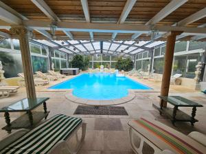 a large swimming pool with chairs and a glass ceiling at La Maison Coloniale - 15 Personnes - Piscine in Artagnan