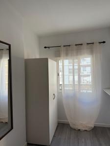 a white room with a mirror and a window at Avenue Rooms in Valencia