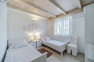a white bedroom with two beds and a chair at Beachfront House Mir Brač near Supetar with pool and jacuzzi in Mirce