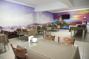 ein Restaurant mit Tischen und Stühlen und einem großen Gemälde an der Wand in der Unterkunft Ramparts Hotel in Istanbul