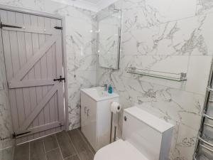 a white bathroom with a toilet and a mirror at Corner Cottage in Haverfordwest +13 photos