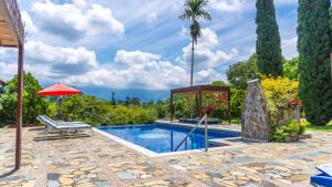 a swimming pool with a palm tree and an umbrella at Hotel Campestre Solar De La Luna in Armenia