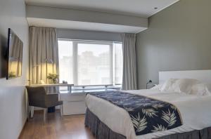 a bedroom with a bed and a desk and a window at Regency Golf - Hotel Urbano in Montevideo +25 photos