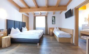 a hotel room with two beds and a tv at Guesthouse Dolomiten in Egna