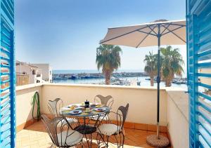 a table with chairs and an umbrella on a balcony at Solemar Sicilia - Palazzo Eos e Aura in Porticello