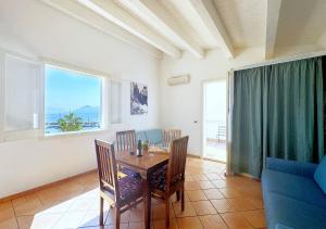 a dining room with a table and chairs and a couch at Solemar Sicilia - Palazzo Eos e Aura in Porticello