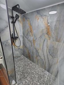 a bathroom with a shower with a marble wall at Apartment 3 by Villa Ceni in Elbasan