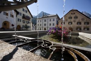 a fountain in the middle of a town with buildings at Plavna Apartment in Scuol