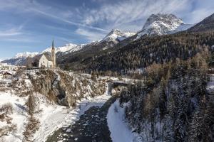 a church on a mountain with snow covered mountains at Plavna Apartment in Scuol