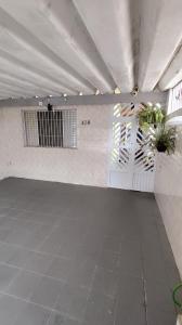 a room with a white wall with plants on it at Casa Amarelinha da Tupi in Praia Grande