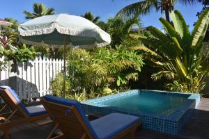 a swimming pool with two chairs and an umbrella at Ambiance Villa in La Digue