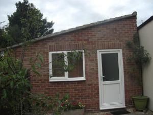 a red brick house with a white door at Garden Apartment in Didcot