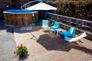 a deck with chairs and a hot tub and an umbrella at Gîte Le Charme in Aspach-le-Bas