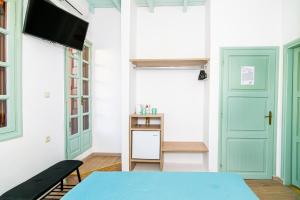 a room with green doors and a table and a tv at Alegria Pension in Chania