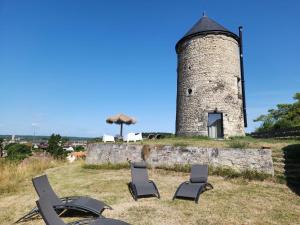 a group of chairs sitting in front of a tower at Le Moulin de la Motte Baudoin in Noyers-sur-Cher +5 photos