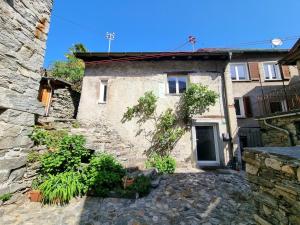 an old stone house with a door and a yard at Wild Valley Rustico Piazza in Intragna, Centovalli in Intragna