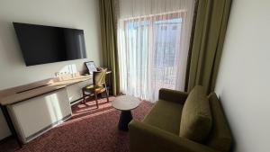a living room with a green couch and a television at Regina Hotel in Druskininkai