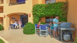 a man standing in a patio with a grill and people at Ground Floor 2BR Beachfront - Steps to Pool - Princesa E104 - BeachBumCondos in Puerto Peñasco