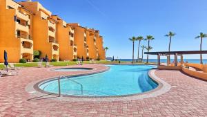 a swimming pool in front of a building at Ground Floor 2BR Beachfront - Steps to Pool - Princesa E104 - BeachBumCondos in Puerto Peñasco
