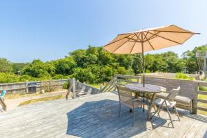 a table and chairs with an umbrella on a deck at 4601 - Sandy Bluff in Southern Shores