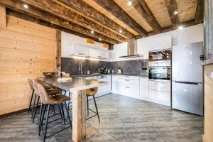 a kitchen with white cabinets and a wooden ceiling at Chalet Liloo sous la neige in Saint-Sorlin-dʼArves