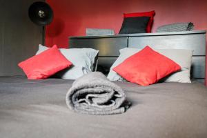 a bed with red pillows and a blanket on it at Suite CinéRoom à 25 min de Paris in Franconville